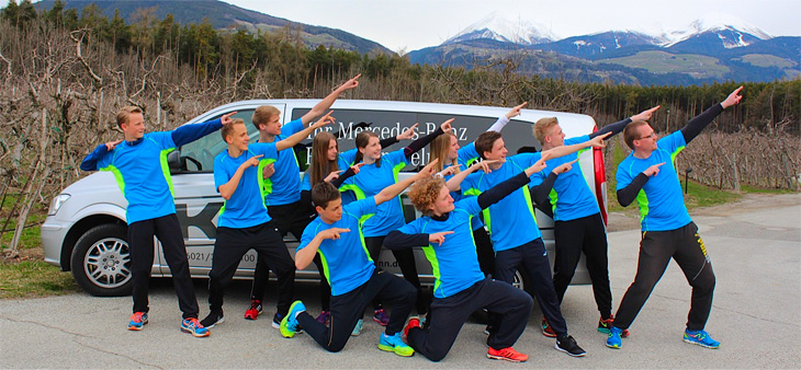 
Gruppenfoto der Athletinnen und Athleten mit ihrem Trainer Markus Günther vor einem Auto.<br />
